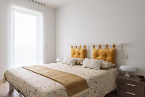 una camera bianca con un grande letto con cuscini gialli di JOIVY UpTown Flats with Balcony, Good Connection to Milan Centre a Milano