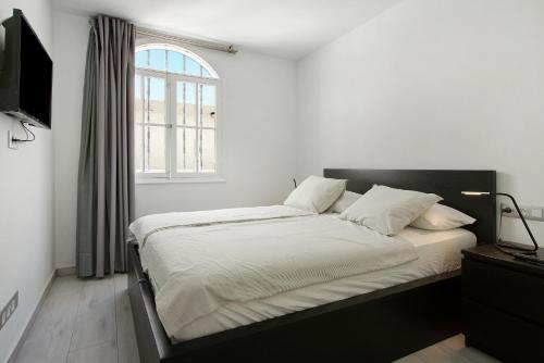 Una cama con sábanas blancas y una ventana en una habitación en Casa Princesa, en Playa del Cura