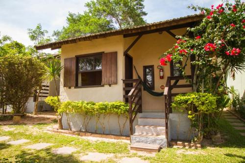 a small house with red flowers in front of it at Pousada Mares do Santinho in Florianópolis