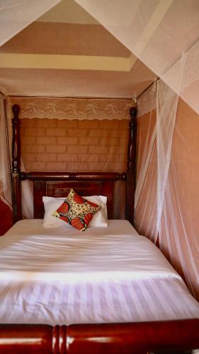 a bed with a wooden headboard with a pillow on it at SINA Village in Mpigi