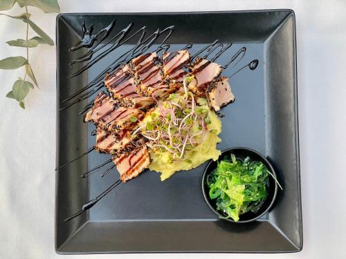 a plate of food with meat and a bowl of lettuce at Hotel Ponteo - Activity Park in Bratislava