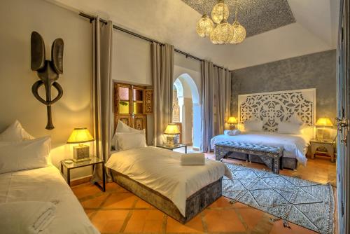 a bedroom with two beds and a chandelier at Riad Dar Fanny in Marrakesh