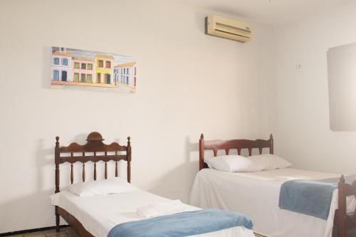 two beds in a room with a painting on the wall at Hotel Pousada Calhau in São Luís