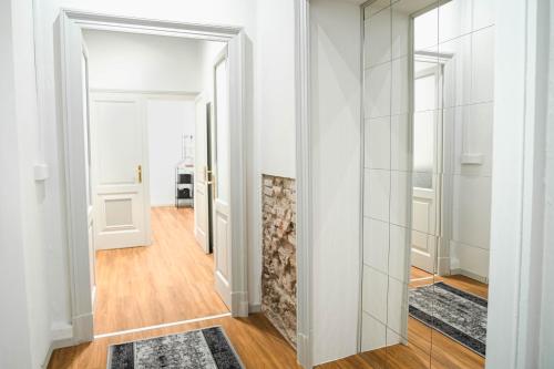 a hallway with white walls and wood floors and a mirror at The Host in Parma