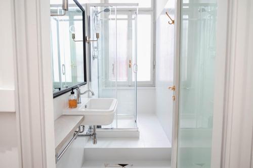 a white bathroom with a sink and a shower at The Host in Parma