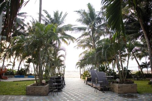 a resort patio with chairs and palm trees on the beach at Beach Studio @ Cowrie in Mombasa