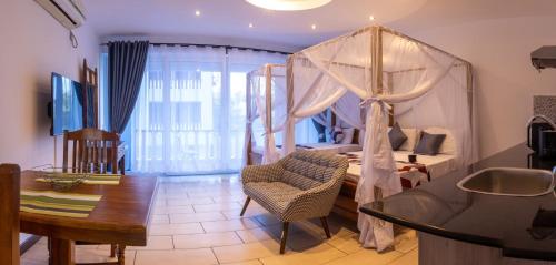 Beach Studio @ Cowrie في مومباسا: غرفة نوم بسرير مظلة وطاولة وكرسي