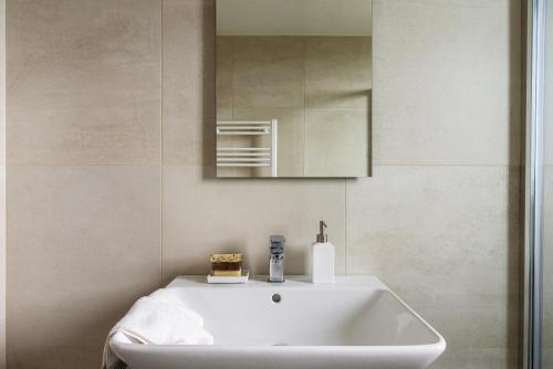 bagno con lavandino bianco e specchio di JOIVY UpTown Flats with Balcony, Good Connection to Milan Centre a Milano