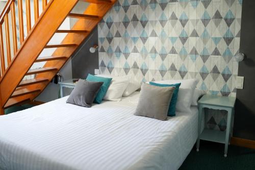 a bedroom with a bed with pillows and a staircase at Hôtel Picardia in Saint-Valery-sur-Somme