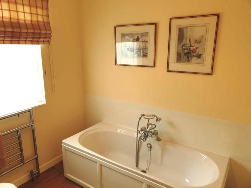 a bathroom with a tub with two pictures on the wall at Lochs Lodge, Glenlyon, Perthshire 
