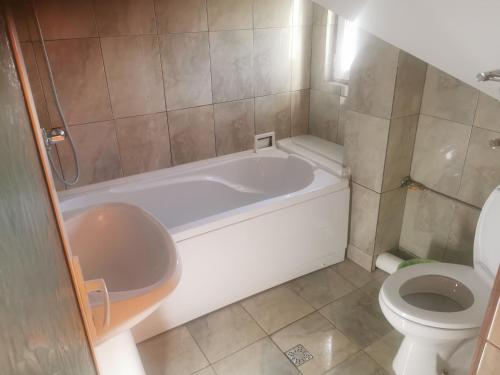 a bathroom with a white tub and a toilet at PENSIUNEA EDWARD in Eforie Sud