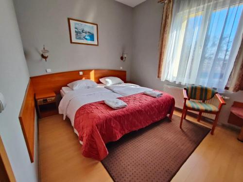 a bedroom with a bed with a red blanket and a chair at Delta In in Dzierżoniów
