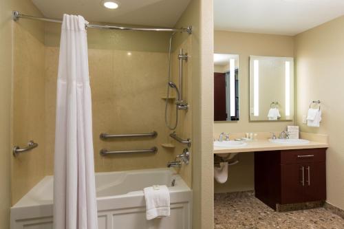 a bathroom with a shower and a tub and a sink at Staybridge Suites Las Vegas - Stadium District in Las Vegas