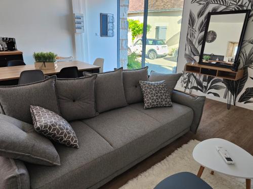 ein Wohnzimmer mit einer grauen Couch und einem Tisch in der Unterkunft Gîte Les Piraudières in Noyant-de-Touraine
