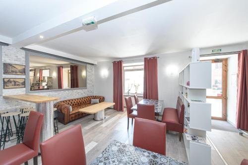 a living room with red chairs and a table at HOTEL DES VOYAGEURS in Pont-de-Roide