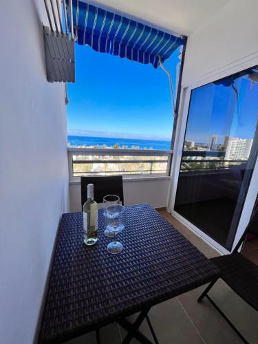 a table with wine glasses and a view of the ocean at Precioso apartamento en 5 minutos de la playa in Playa de las Americas