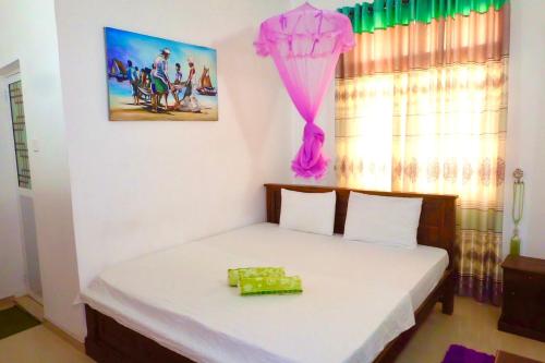 a bedroom with a white bed with a pink drape at Rodrigo's Villa & Restaurant in Negombo