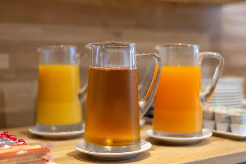 three glasses of orange juice sitting on a table at Hotel Mimosa Paris in Paris