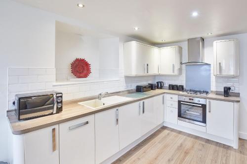 a white kitchen with white cabinets and a microwave at Host & Stay - Park Base in Tynemouth