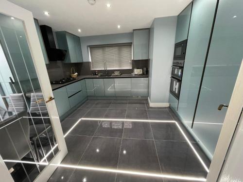 a kitchen with blue cabinets and a tiled floor at Cheerful 4 Bedroom luxury house with free parking in Quinton