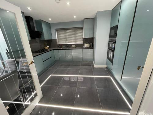 a kitchen with blue cabinets and a tiled floor at Modern 4 Bedroom Stylish Villa with out-door Hot Tub in Quinton