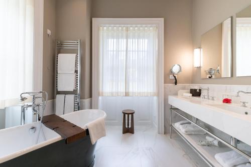 a white bathroom with a tub and a sink at Casa Velha do Palheiro Relais & Chateaux in Funchal