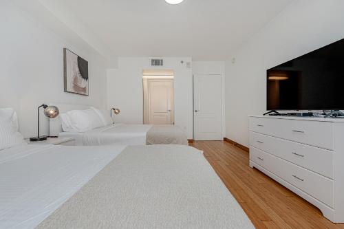 a white bedroom with two beds and a sink at Lovely condo with city & ocean views. Sleep up to 6 people! in Miami