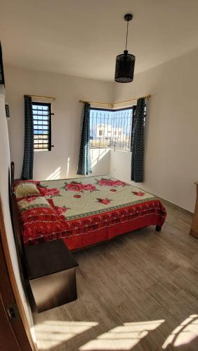 a bedroom with a bed with a red blanket and two windows at Coquette villa avec piscine in Flic-en-Flac