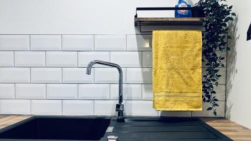 um lavatório de cozinha com uma toalha amarela numa prateleira em ☆ The Cottage - Cosy 1 bedroom, central location ☆ em Harrogate