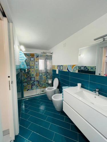 un bagno blu e bianco con due servizi igienici e un lavandino di La Casetta di Sasá a Procida