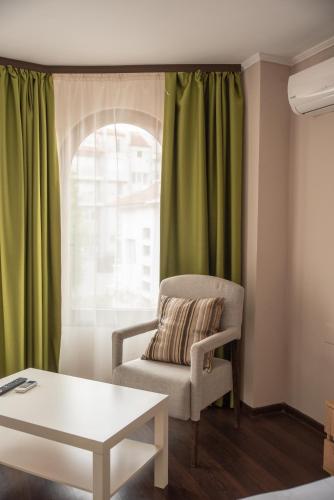 a living room with a chair and a window at Hotel Oppium Restaurant & Garden in Ruse