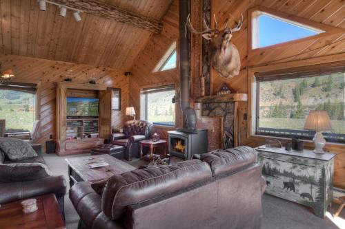 a living room with leather furniture and a deer head on the wall at Bristol Head Acres Rustic Cabin in Creede