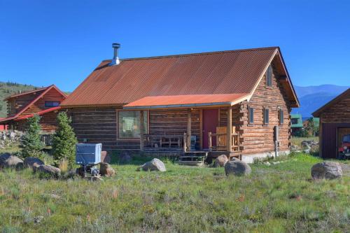 a log cabin in a field next to a house at Bristol Head Acres Rustic Cabin in Creede