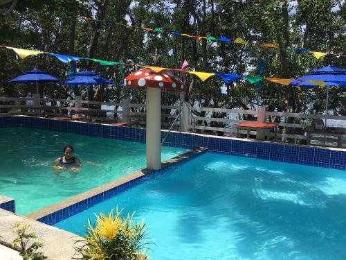 a woman swimming in a swimming pool with umbrellas at Kang-JoLu's Camotes Homestay in Camotes Islands