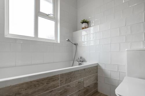 a white bathroom with a tub and a window at Grove Avenue in Norwich