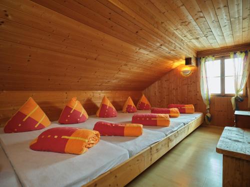 a large bed in a wooden room with colorful pillows at Neuhornbachhaus in Schoppernau