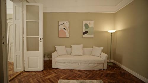 a living room with a white couch and a lamp at Allegro apartments city center in Oradea