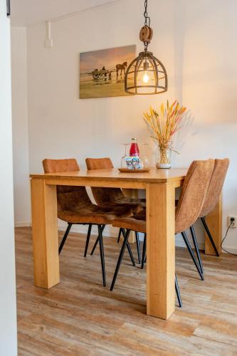 a dining room table with chairs and a light fixture at Terschelling Natuurlijk in Kinnum