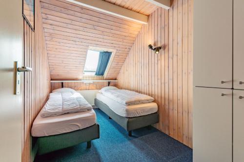 two beds in a small room with wooden walls at Terschelling Natuurlijk in Kinnum