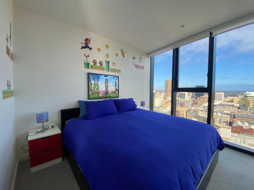 Nintendo Theme-Adelaide CBD-King Bed-Spa-Gym-BBQ في أديلايد: غرفة نوم بسرير ازرق ونافذة كبيرة