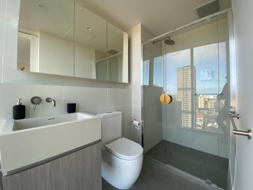 a bathroom with a toilet and a sink and a window at Nintendo Theme-Adelaide CBD-King Bed-Spa-Gym-BBQ in Adelaide