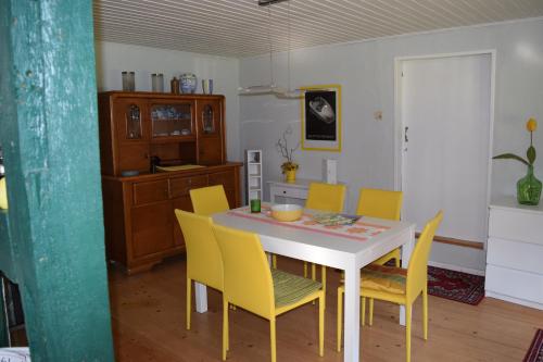 a dining room with a white table and yellow chairs at Wohnung Waltraud in Plattenburg