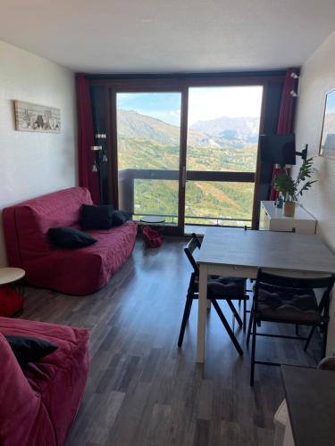 een woonkamer met een rode bank en een tafel bij Studio au pied des pistes 4 pers, Alpes Le Corbier in Le Corbier