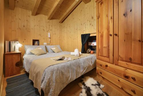 - une chambre avec un lit et un mur en bois dans l'établissement Casa Alpina San Luigi, à Campodolcino