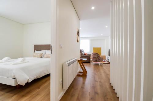 a white bedroom with a bed and a living room at Senhora dos Mares - Apartment in Ribeira in Viana do Castelo