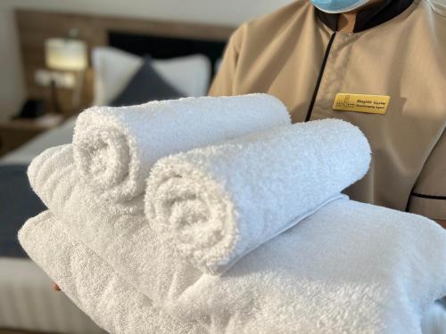 a person wearing a mask holding a pile of towels at The Proud Hotel Al Khobar in Al Khobar