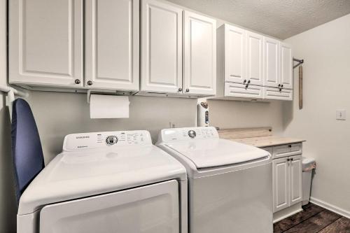 cocina con armarios blancos, lavadora y secadora en Fayetteville Retreat with Hot Tub and Fenced Yard en Fayetteville