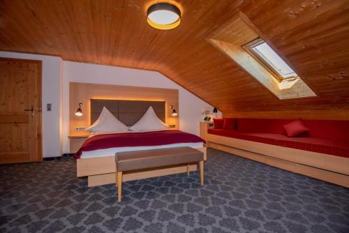 ein Schlafzimmer mit einem großen Bett und einem roten Sofa in der Unterkunft Pension Ludwig Thoma in Otterfing