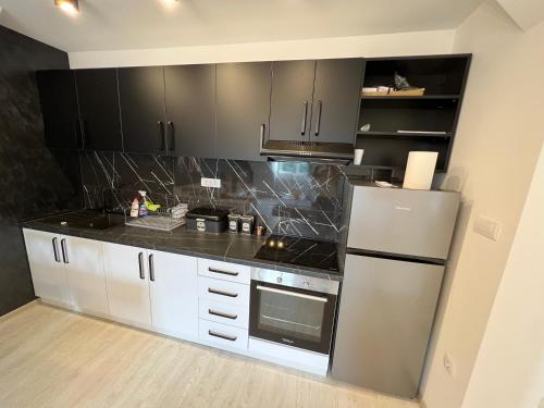 a kitchen with black cabinets and a stainless steel refrigerator at Lux Apartman Rudnik in Rudnik Kačerski