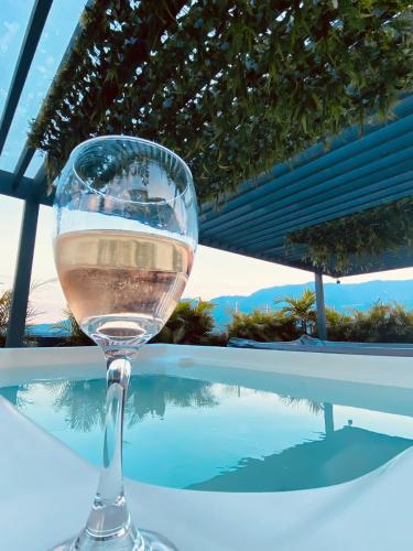 a glass of wine sitting on a table next to a pool at Hotel Doral Inn in Ibagué